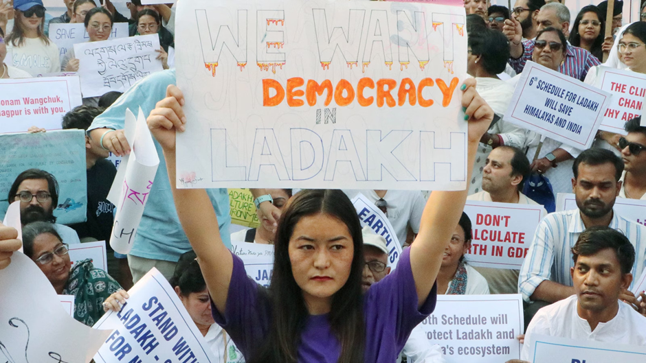 Woman holding 'we want democracy in Ladakh' placard